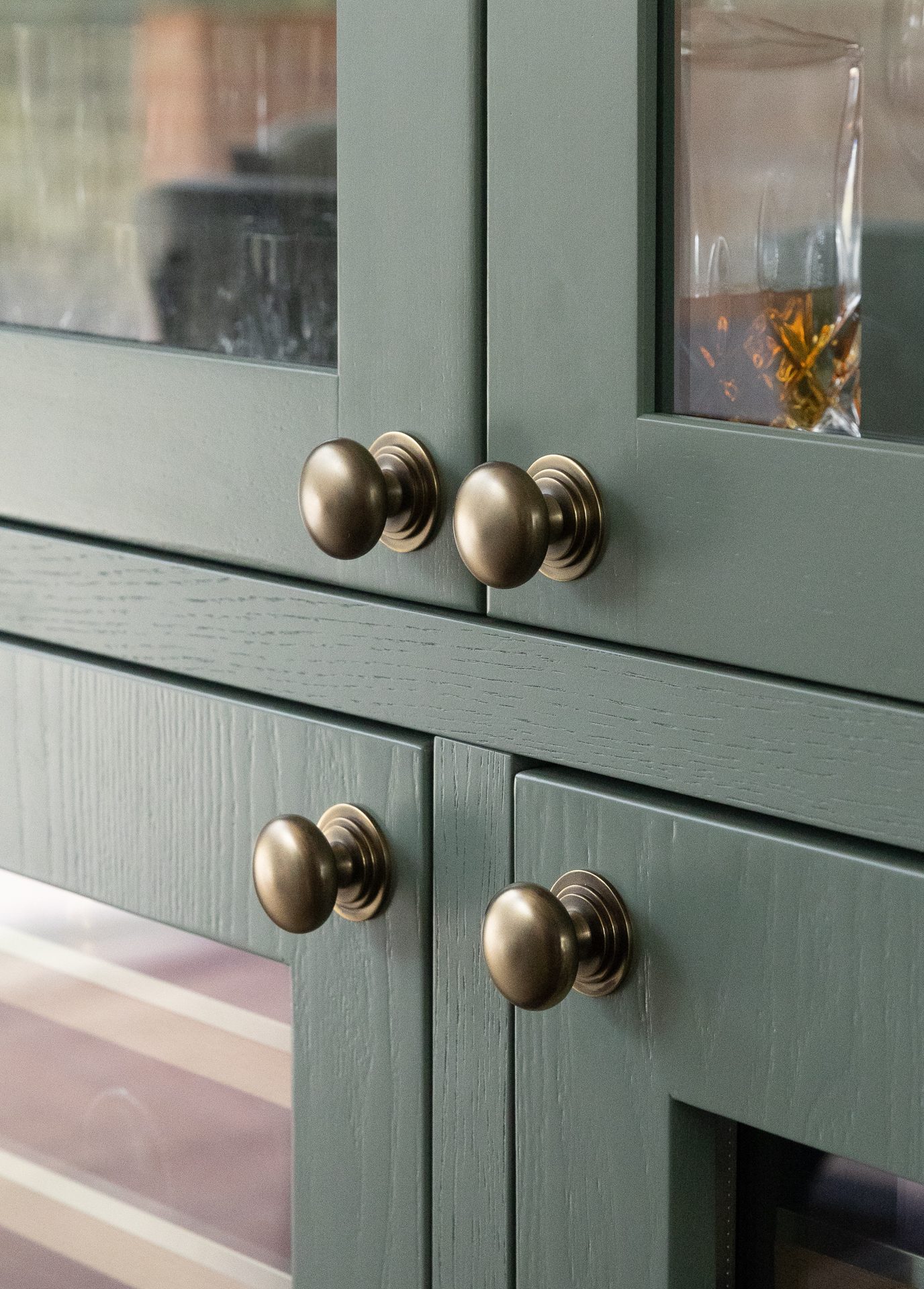 Antique nickel cabinet knobs on sage green Shaker cabinets with visible oak grain
