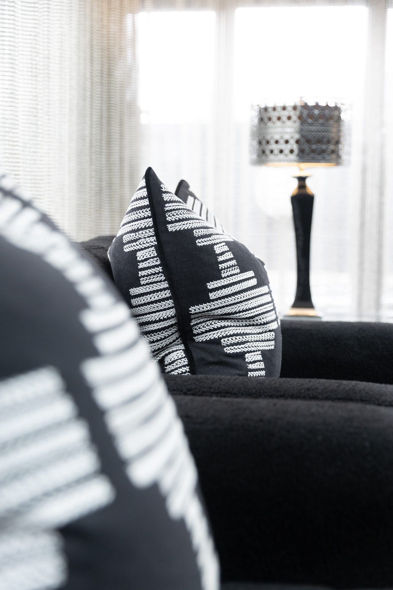 A stack of cable-knit and linen cushions in cream and charcoal