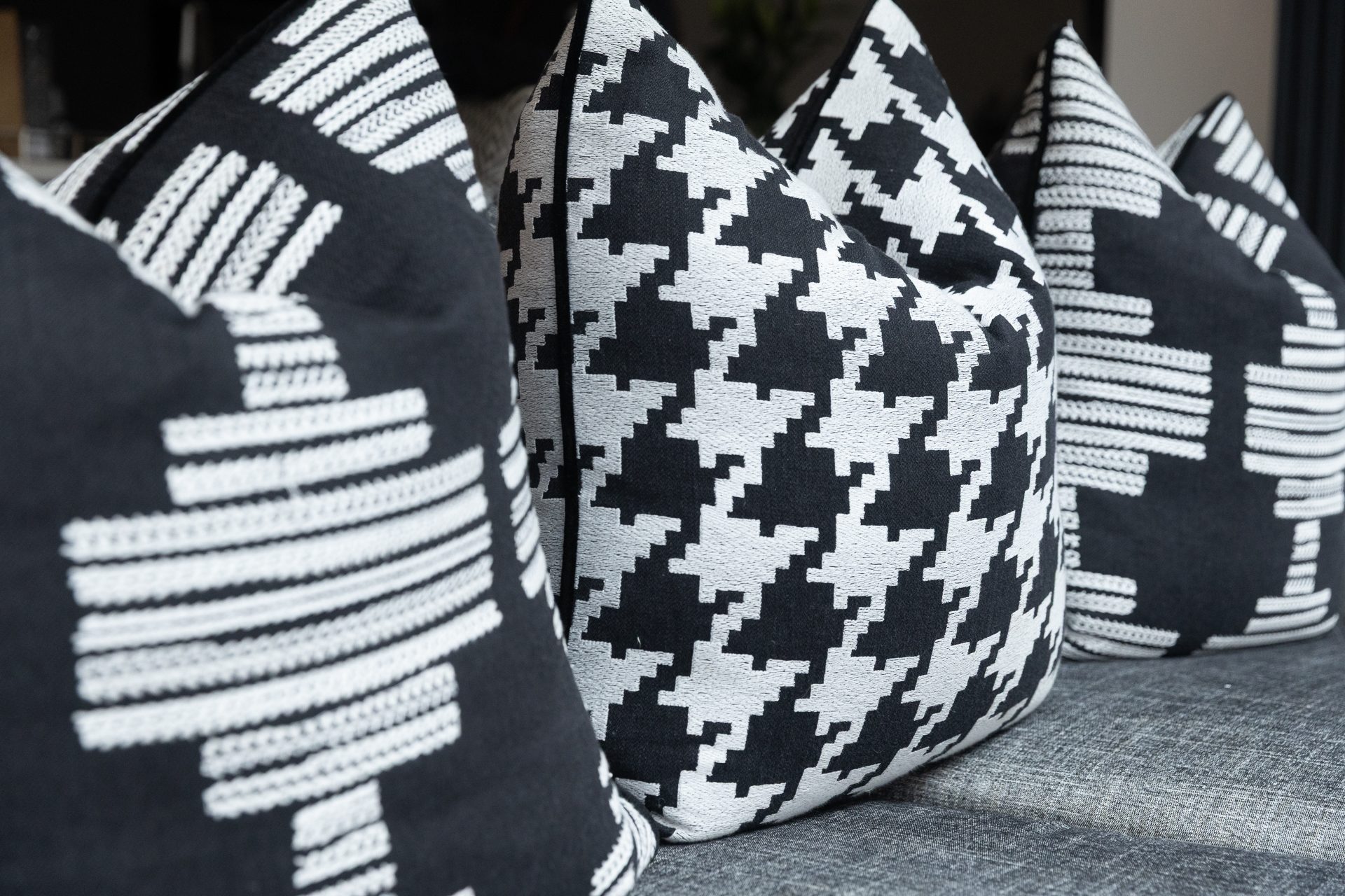 A row of black-and-white cushions including a bold houndstooth in the centre, flanked by black cushions with embroidered white motifs, header image for the Pattern chapter