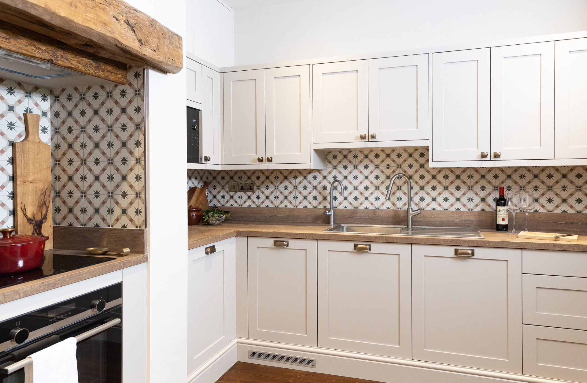 The Bamburgh kitchen, cream shaker cabinetry, star-patterned tiles and a reclaimed oak lintel over the cooker