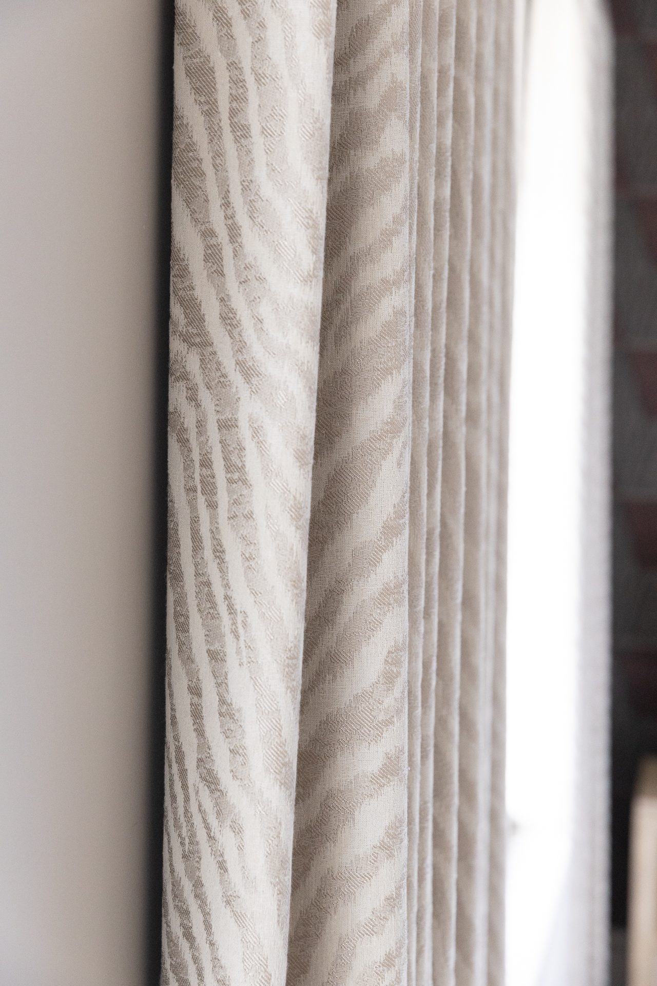 Curtain detail in the guest bedroom, natural light filtered through a heavy weave