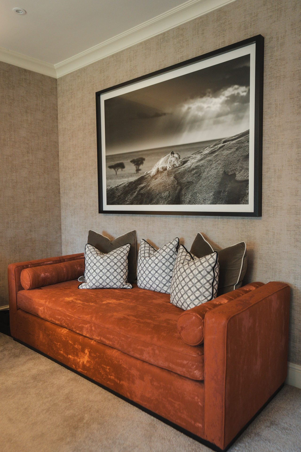 The reading corner in the bedroom, a russet velvet sofa with a black-framed print of a lion hanging above
