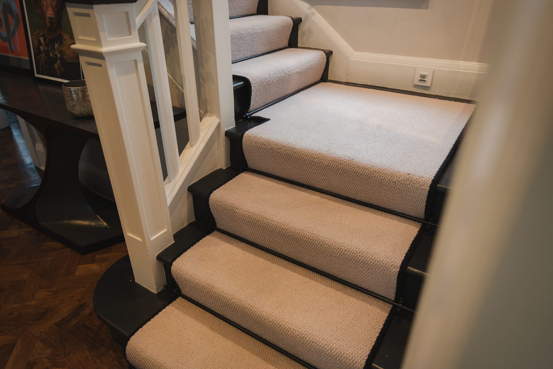 Tight detail of the cream stair runner on the dark oak tread, the black nosing between them