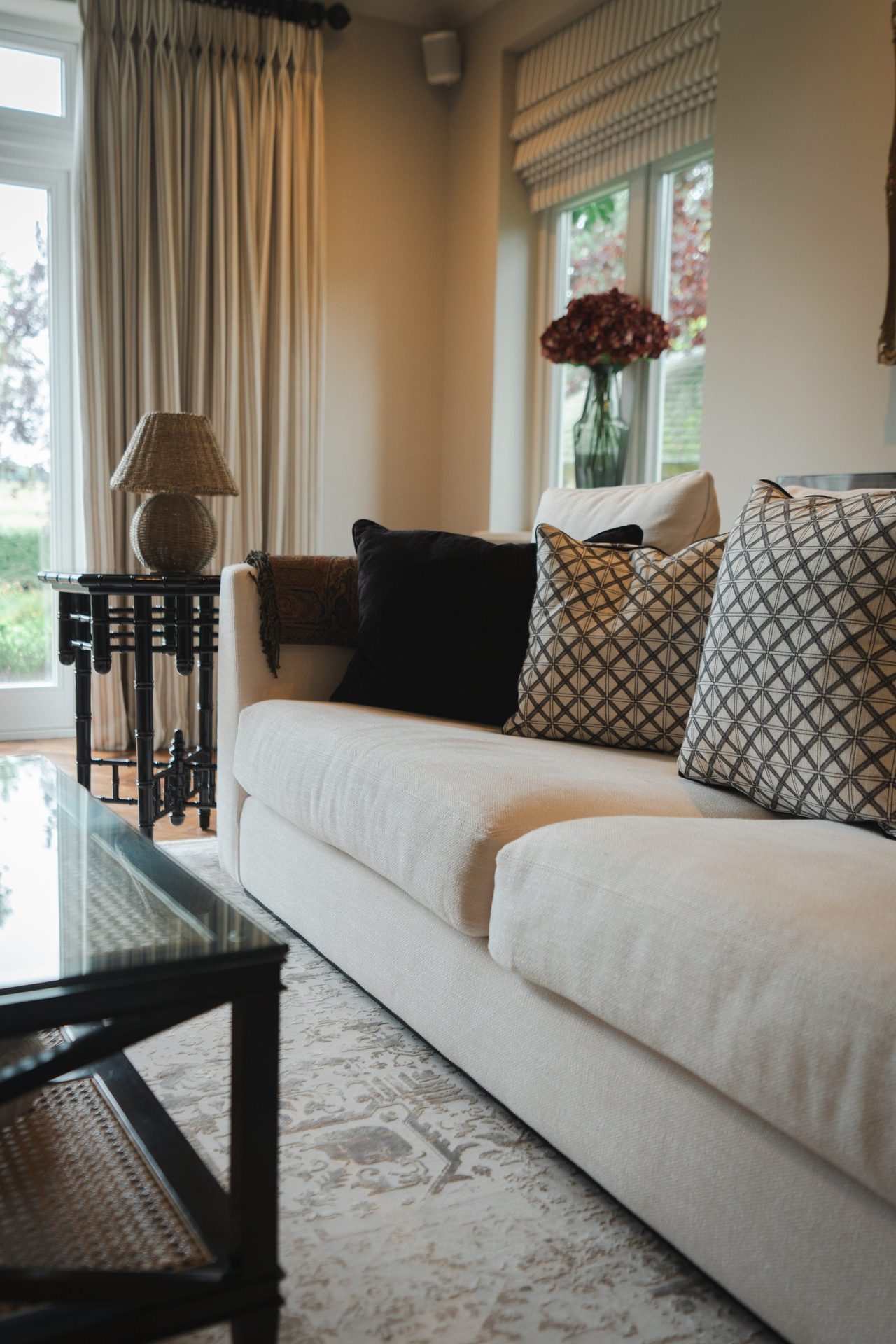 The living room bay window with linen curtains, an oak side table and a styled vase