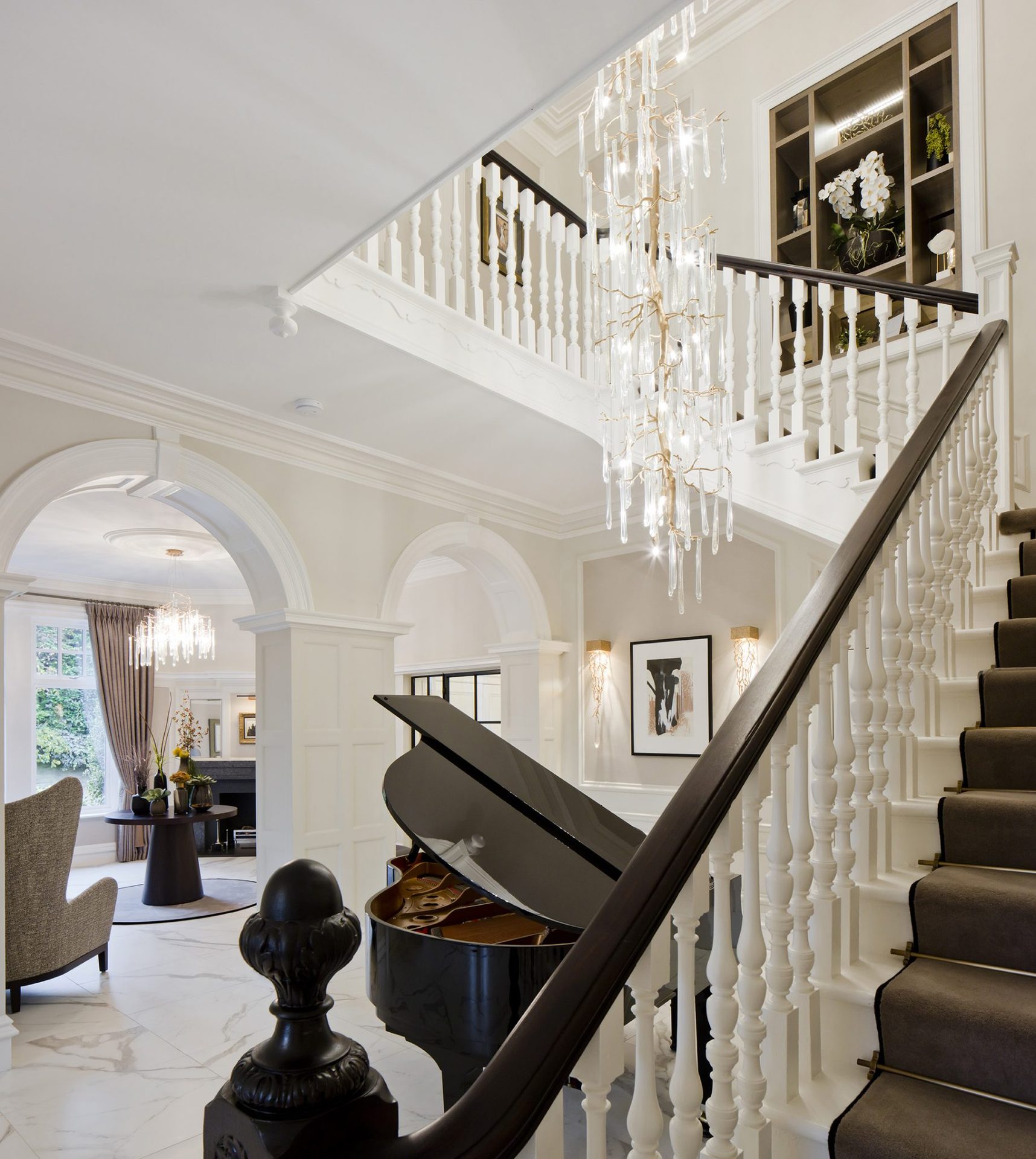 The piano lounge, featuring a grand piano and a statement pendant fitting set against pale stone and high ceilings