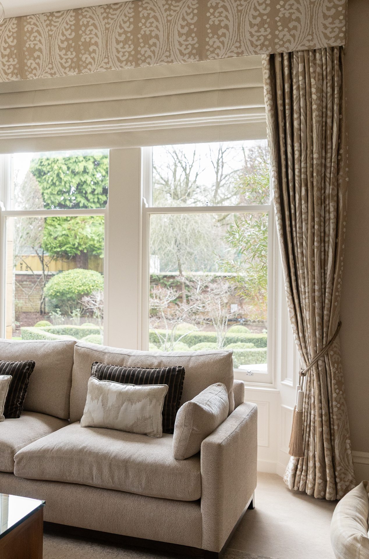 The Springfield bay window, Roman blind, patterned pelmet, draped curtains over a garden view