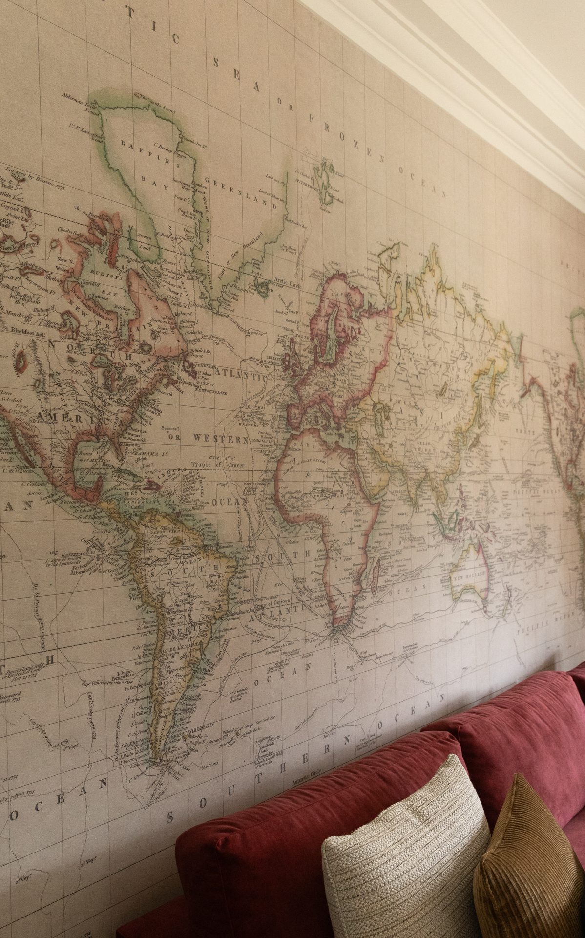 The Springfield lounge, vintage world map wallpaper with a burgundy velvet sofa