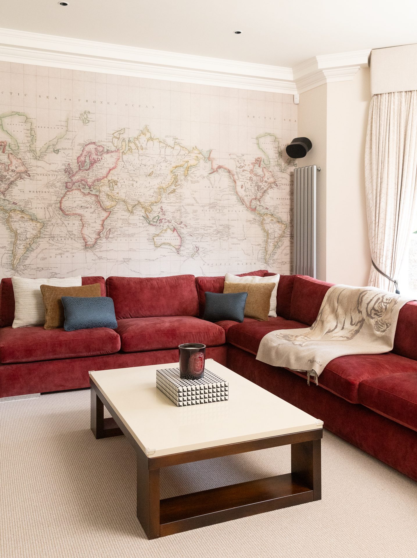 The Springfield lounge held in portrait, red velvet against the cartography wall, a candle and a small box on the coffee table