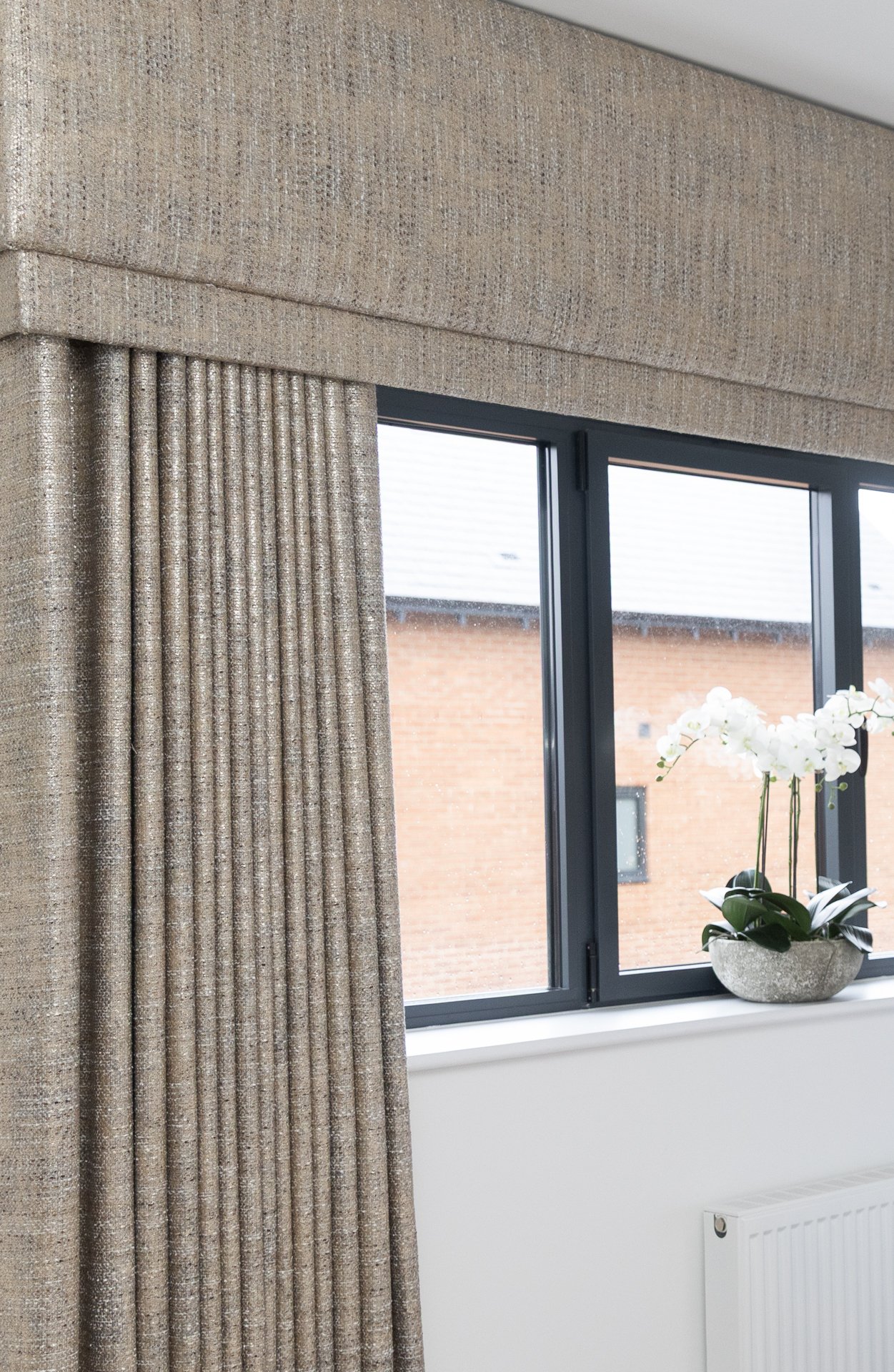 Close detail of the textured linen pelmet and drape, white orchid just in frame below
