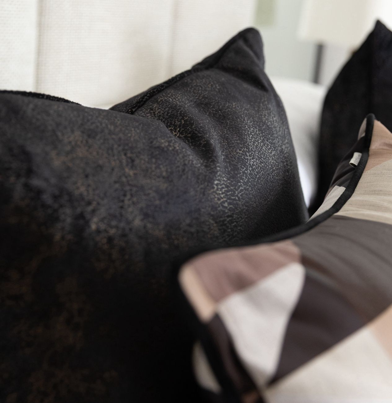 A close detail of a distressed black leather-look cushion, the upholstery weight Warwick is known for